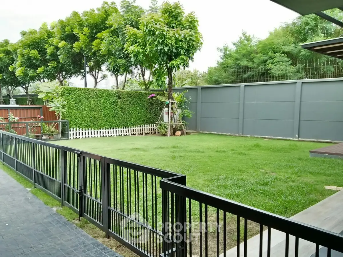 Spacious garden with lush greenery and modern fencing in a serene residential area.