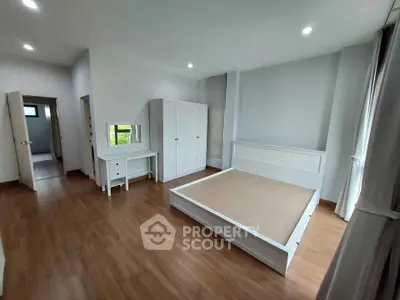 Spacious bedroom with wooden flooring and modern white furniture