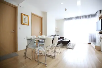 Modern living room with dining area, featuring sleek furniture and abundant natural light.