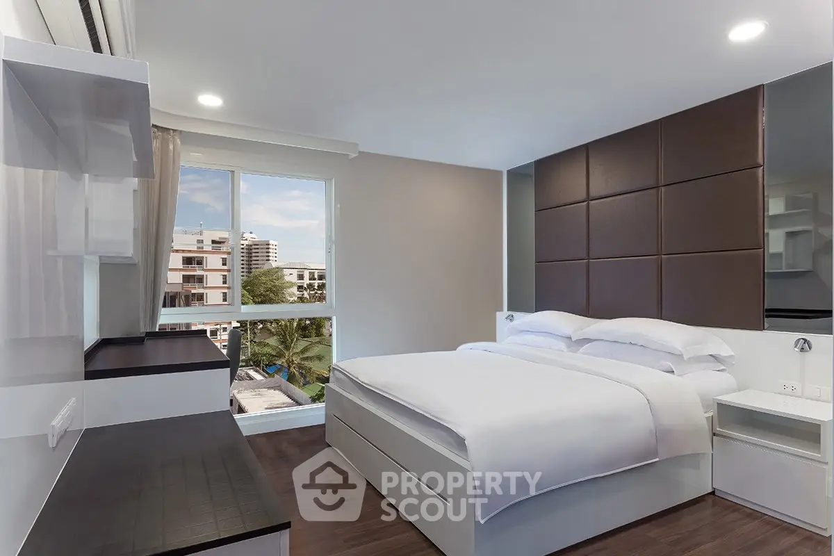 Modern bedroom with elegant design and large window offering a stunning view of the cityscape.