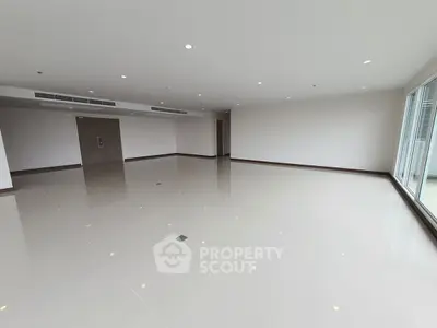 Spacious modern living room with glossy tiled floors and large windows for natural light.