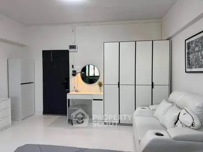 Modern minimalist bedroom with sleek white furniture and cozy seating area.