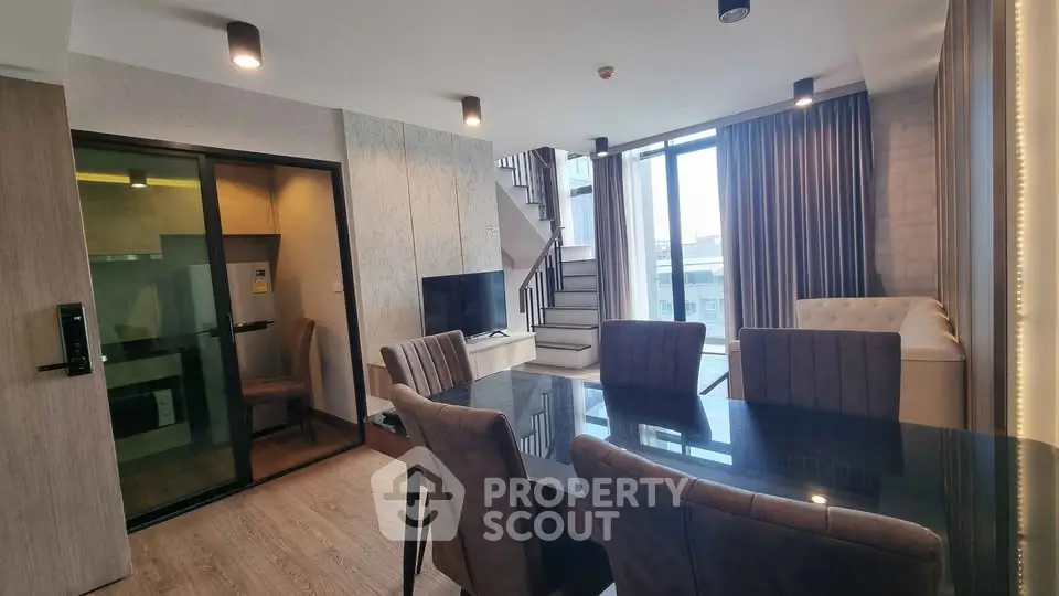 Modern duplex living room with elegant dining area and large windows offering natural light.