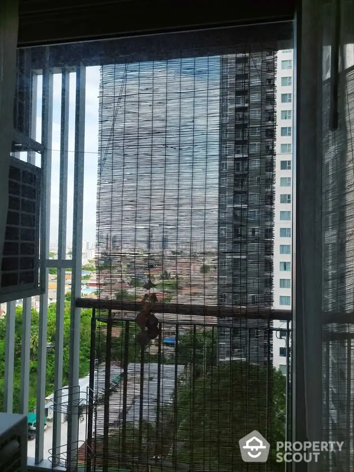 City view from apartment window with bamboo blinds and urban skyline.