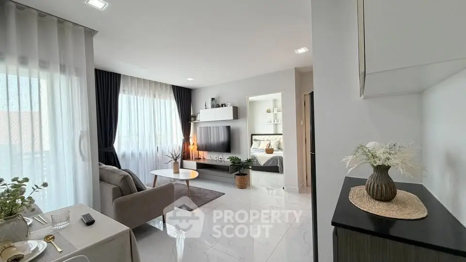 Modern living room with elegant decor and natural light, featuring a cozy seating area and stylish TV setup.