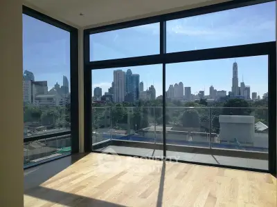 Spacious modern living room with floor-to-ceiling windows offering stunning city skyline views.
