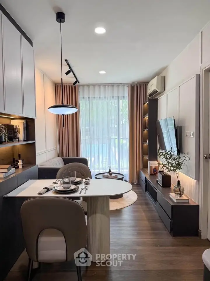 Modern living room with stylish decor and natural light, featuring a cozy dining area and sleek entertainment setup.