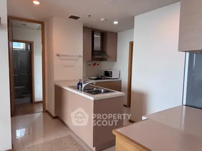 Modern kitchen with sleek cabinetry and stainless steel appliances in a cozy apartment.