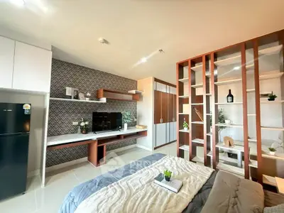 Modern studio apartment with stylish decor and open shelving, featuring a cozy bed and sleek entertainment area.