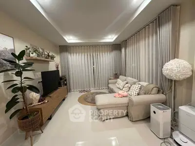 Modern living room with cozy sofa, TV, and stylish decor in a well-lit space.
