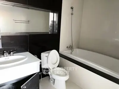 Modern bathroom with sleek black and white design featuring bathtub and vanity.
