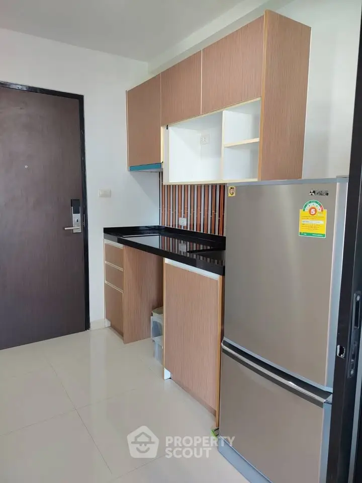 Modern kitchen with sleek cabinetry and stainless steel fridge in a compact layout.