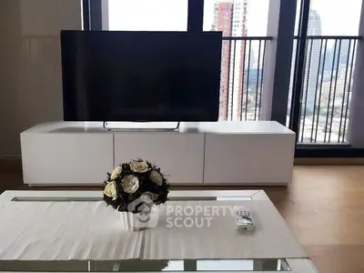 Modern living room with sleek TV setup and city view balcony, perfect for urban living.