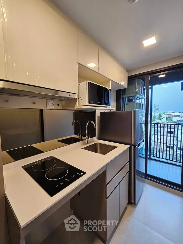 Modern kitchen with sleek appliances and balcony view in urban apartment