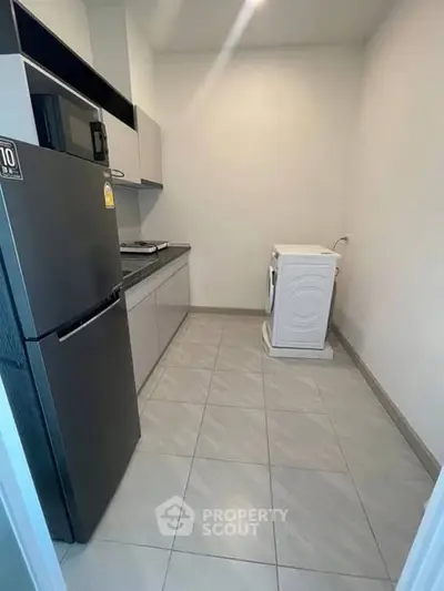 Modern kitchen with sleek appliances and washing machine in compact layout.