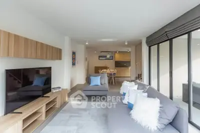 Spacious modern living room with large TV and stylish decor, open to dining area and kitchen.