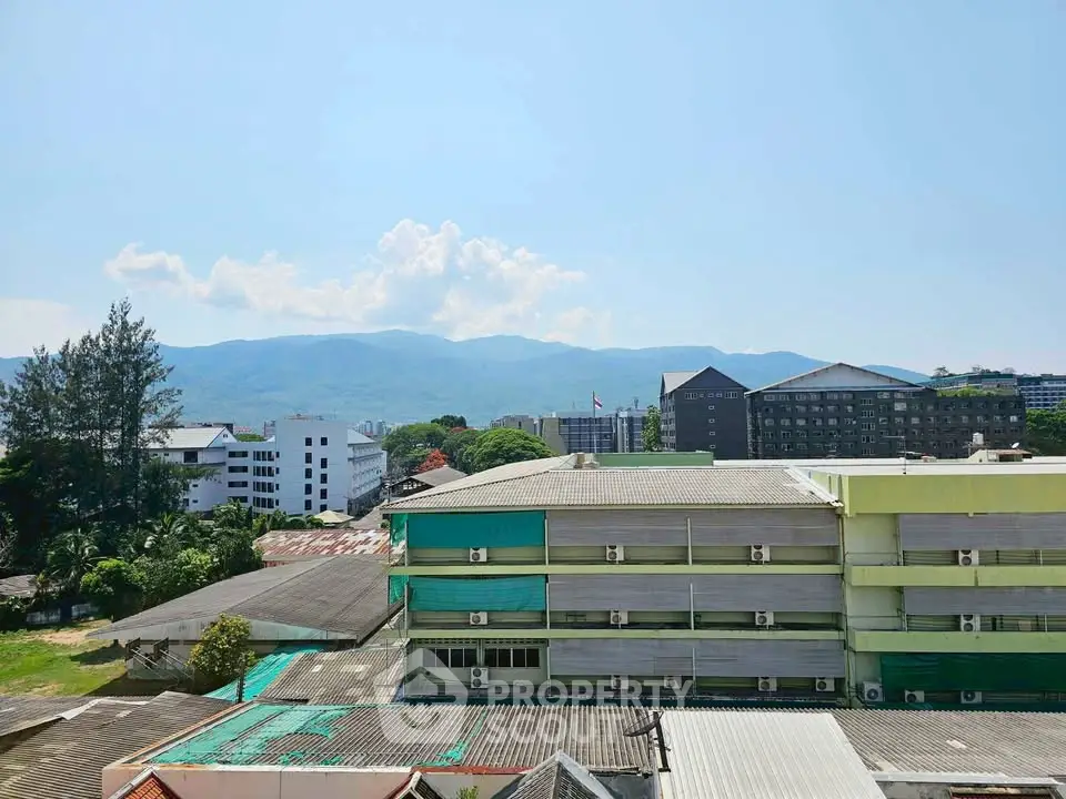 Scenic view of urban buildings against a mountain backdrop on a clear day.