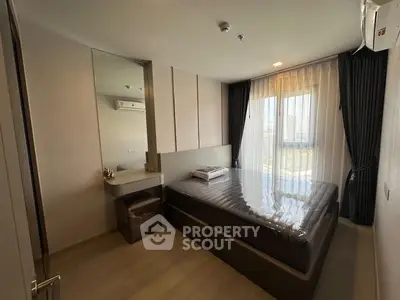 Modern bedroom with large window and sleek furnishings in a contemporary apartment.