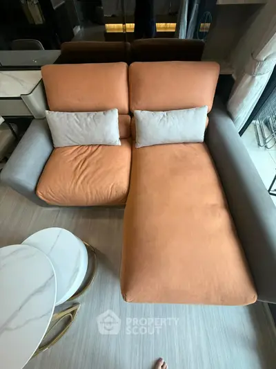 Modern living room with stylish orange and gray sofa and elegant marble coffee table.