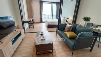 Modern open-plan living room with stylish furniture and a cozy bedroom area.