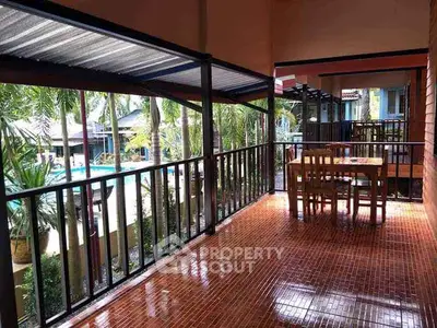 Spacious balcony with pool view in tropical setting, perfect for relaxation.