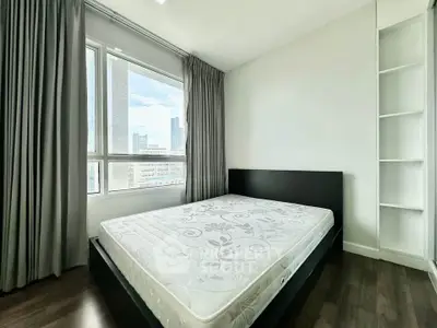 Modern bedroom with large window and built-in shelving, offering city views and ample natural light.