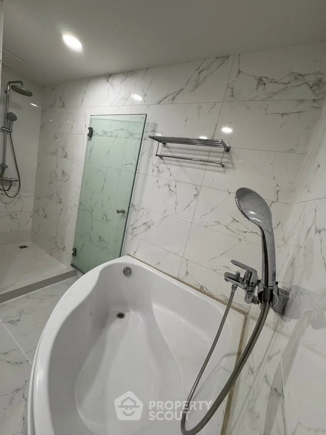 Luxurious bathroom with marble tiles and modern fixtures, featuring a spacious bathtub and sleek shower area.