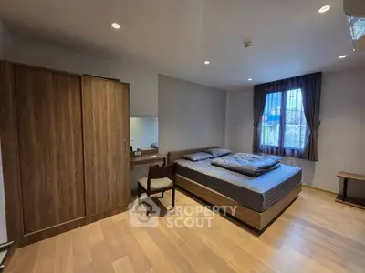 Spacious modern bedroom with wooden flooring and large window