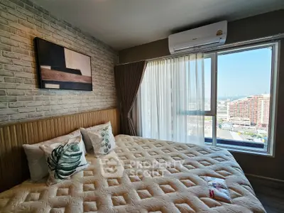 Spacious bedroom with large window offering stunning city view and modern decor.