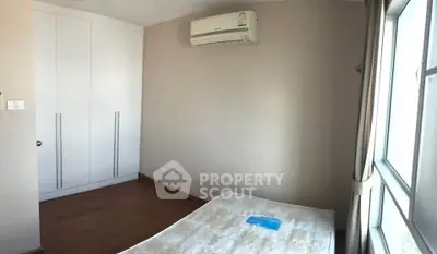 Cozy bedroom with built-in wardrobe and air conditioning, featuring natural light from large window.