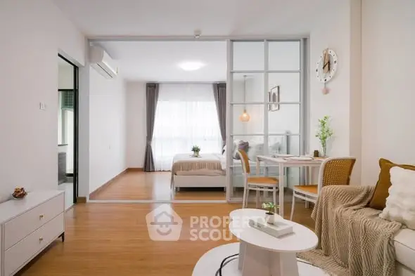 Modern open-plan living room with cozy decor and glass partition to bedroom.