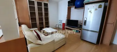 Cozy living room with modern furniture and stainless steel fridge, perfect for urban living.