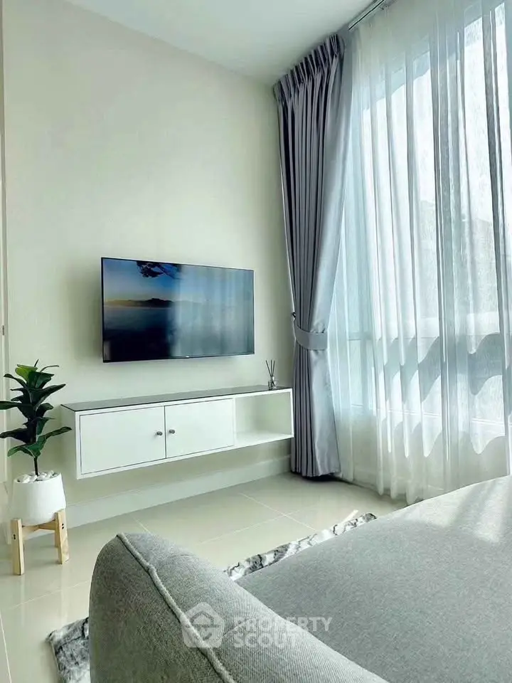 Modern living room with sleek TV setup and large window with elegant curtains.