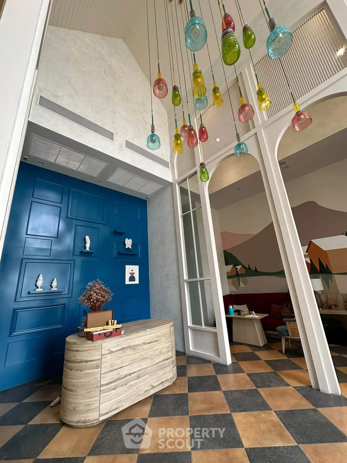 Stylish lobby with colorful pendant lights and modern decor, featuring a blue accent wall and unique furnishings.