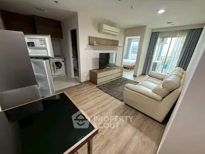 Modern living room with open kitchen, featuring sleek furniture and appliances, ideal for urban living.