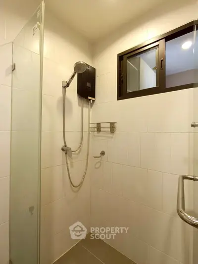 Modern bathroom with glass shower enclosure and window for natural light.