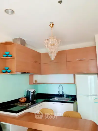 Modern kitchen with sleek cabinetry, elegant chandelier, and integrated appliances in a stylish open layout.