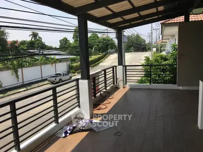 Spacious balcony with wooden flooring and street view, perfect for relaxation.