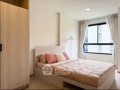 Cozy bedroom with modern decor and large window offering natural light