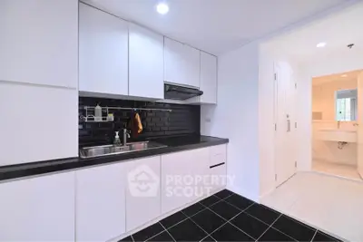 Modern kitchen with sleek black and white design, featuring ample storage and contemporary fixtures.