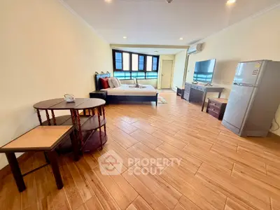 Spacious studio apartment with modern furnishings and large windows for natural light.