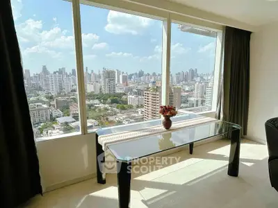 Stunning cityscape view from modern apartment with large windows and elegant glass table.