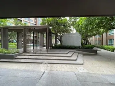 Modern apartment complex entrance with landscaped garden and stylish architecture.