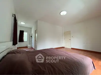Spacious bedroom with wooden flooring and natural light