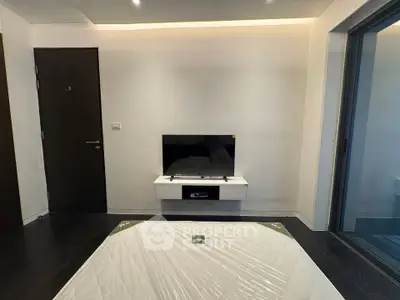 Modern bedroom with wall-mounted TV and sliding glass door to balcony
