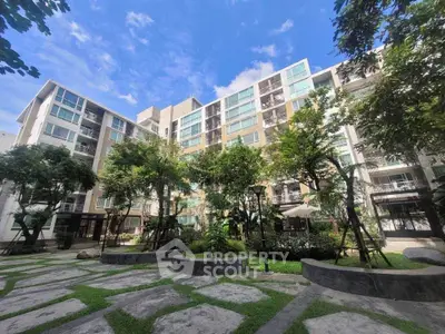 Modern apartment building with lush garden and clear blue sky