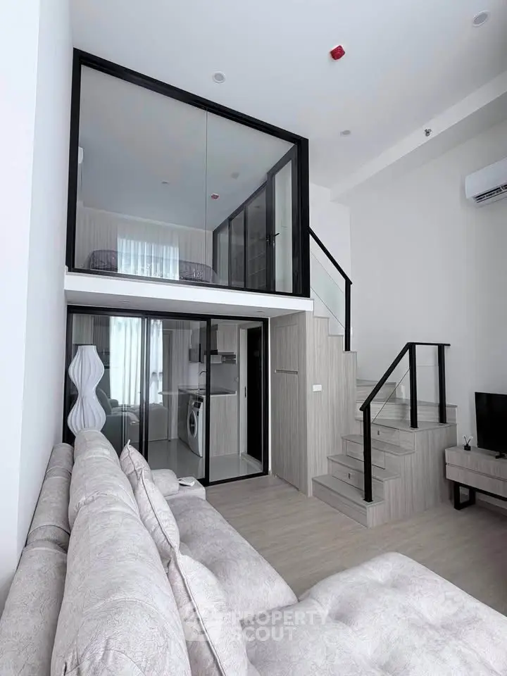 Modern loft apartment with mezzanine, stylish living area, and sleek staircase.