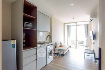 Modern apartment interior with open layout, featuring a compact kitchen and cozy living area leading to a balcony.