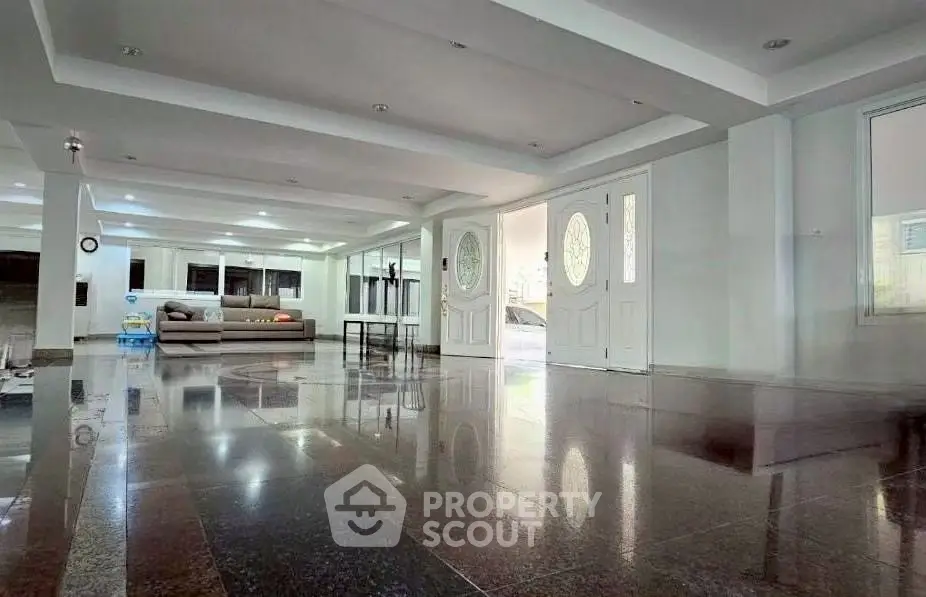 Spacious living room with glossy flooring and elegant double doors, perfect for modern living.