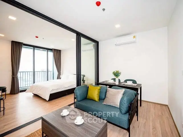 Modern open-layout apartment with cozy living area and bedroom, featuring a balcony view.